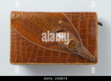 . Enveloppes de cuir de crocodile, allongées avec une tête de crocodile sur la valve dépendante. Le sac a un modèle allongé avec une valve dépendante. Le sac se compose de deux compartiments avec un compartiment central étroit avec fermeture à glissière métallique. Dans la boîte avant un compartiment avec un miroir, un salon sur la couverture arrière. La fermeture sous la valve par bouton-poussoir. À l'arrière du sac, une poignée en cuir crocodile. Le sac est garni de cuir tressé. Doublure en cuir grossièrement et contre le rabat en cuir massif marron. Banque D'Images