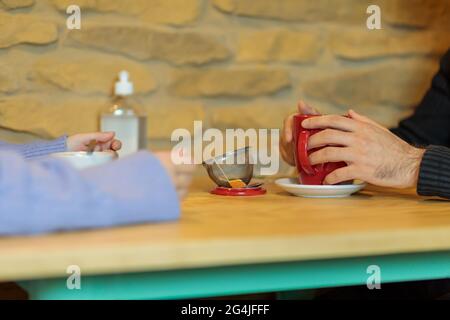 Les mains du couple tiennent leurs boissons chaudes assis dans un café Banque D'Images