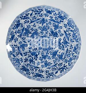. Échelle de porcelaine avec paroi octogonale en pente, peinte en bleu sous-glaçure. Sur l'appartement un chrysanthème stylisé entouré de huit boîtes rayonnantes remplies de diverses plantes à fleurs sur une roche avec des oiseaux; le mur divisé en huit compartiments avec différentes branches de fleurs sur une roche et des oiseaux; le bord avec un motif géométrique. La face arrière est divisée en huit compartiments avec branche de fruits et oiseau. Marqué sur le fond avec une coque dans un double cercle. Bleu blanc. Banque D'Images
