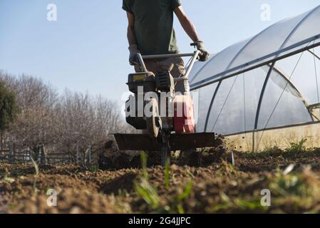 Le fermier prépare le terrain pour le potager d'été avec un couteau Banque D'Images