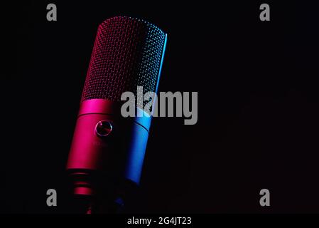 Microphone studio sur fond sombre avec espace de copie. Microphone à condenser professionnel noir avec néon. Enregistrement de podcast Banque D'Images