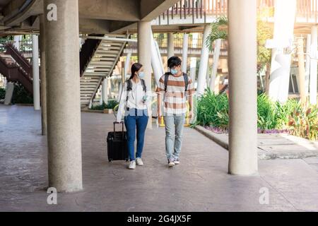 Voyage, homme et femme marchent ensemble pendant le voyage. Parler et regarder des choses à la main. Porter des bagages et des sacs à dos.T-shirt et lunettes abîmés. Banque D'Images