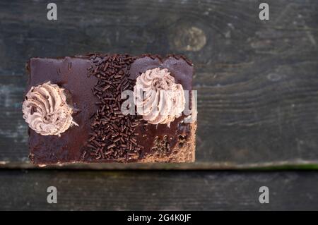 Gâteau en couches, saupoudrés de chocolat et recouverts de doses de crème au chocolat. Pâtisserie sur fond de bois sombre Banque D'Images