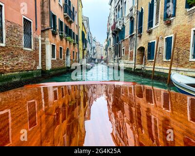 Reflet des maisons sur le capot en bois verni, ponton, du bateau-taxi dans les rues de Venise, qui part Banque D'Images