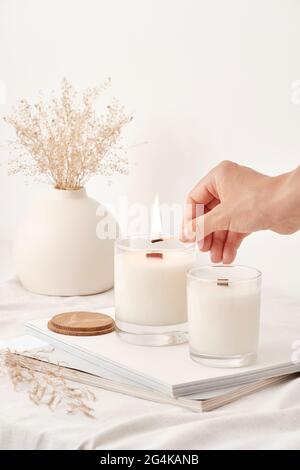 Une fille allume des bougies de cire de soja avec une mèche en bois. Bougies faites à la main. Banque D'Images
