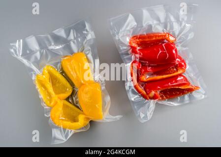 tranches de poivrons rouges et jaunes emballées sous vide scellées pour la cuisson sous vide, isolées sur fond gris Banque D'Images