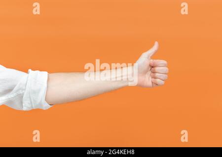 Main d'un homme faisant un signe de pouce sur fond orange. Concept de langage corporel. Signe de main. Comme un geste. Banque D'Images