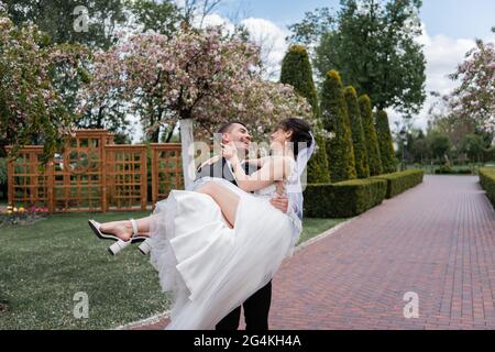 Gaie gaie tenant les mains mariée dans la robe de mariage dans le parc Banque D'Images