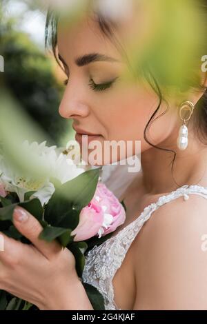 Vue latérale d'une jeune mariée tenant un bouquet sur un premier plan flou Banque D'Images