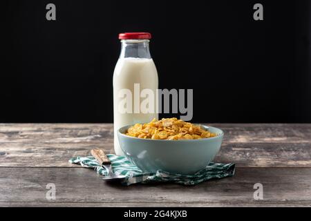 Flocons de maïs dans un bol bleu et bouteille de lait table en bois Banque D'Images