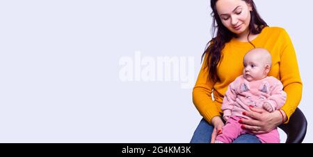 Bannière, format long. Femme avec un bébé. Mère tient une fille dans ses mains sur un fond blanc avec un espace latéral pour la publicité. Banque D'Images