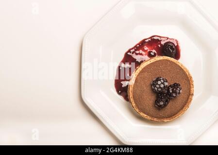Tarte à la Forêt-Noire. Une tarte au chocolat et à la mûre décorée de mûres et d'un coulis / sauce aux fruits de la forêt. Arrière-plan blanc. CopySpace. Banque D'Images