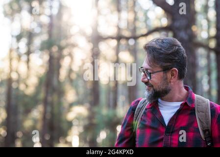 Homme en randonnée et en appréciant dans une forêt de bois. Vue latérale d'un homme portant un sac marchant dans une forêt. Heureux adulte jeune caucasien mâle portra Banque D'Images