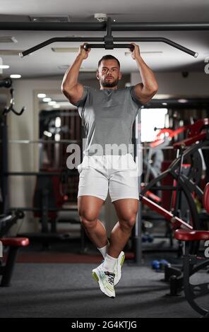 Homme faisant des exercices dans la salle de fitness au bar Banque D'Images