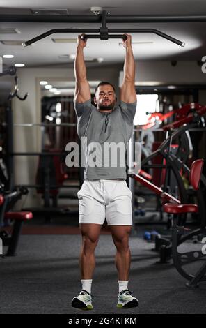 Homme faisant des exercices dans la salle de fitness au bar Banque D'Images