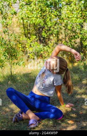 Défocus préadolescence caucasienne pratiquant le yoga dans le parc, la forêt, à l'extérieur, à l'extérieur. Méditation, concentration. Un mode de vie sain. Portrait de la jeune fille de yoga. Banque D'Images