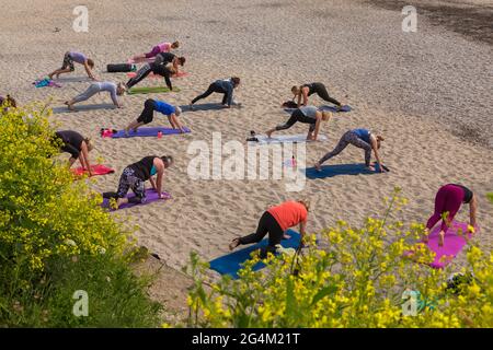 Groupe de femmes faisant du yoga sur la plage de Gyllyngvase à Falmouth, en Cornouailles au Royaume-Uni en juin Banque D'Images