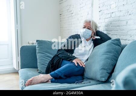 Femme solitaire et triste âgée dans le masque de visage se sentant effrayée, désespéré et déprimé, inquiet au sujet du mari testé positif pour le coronavirus. Fonctionnaire âgé Banque D'Images