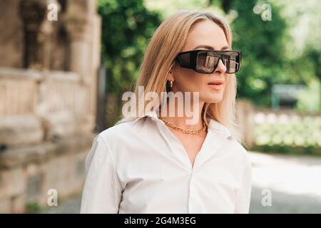 Gros plan Portrait de femme confiante marchant dans la ville, femme entrepreneur portant des lunettes de soleil et regardant loin. Banque D'Images