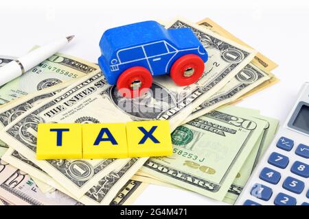 Une voiture bleue, un stylo, une calculatrice et le mot TAXE, se trouve sur un lit de billets en dollars. Une vie financière encore sur le sujet du coût de l'automobile. Banque D'Images