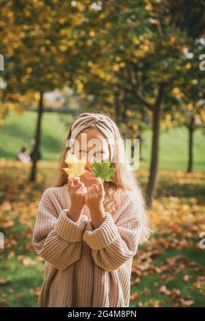 portrait extérieur d'automne de la belle fille heureuse d'enfant marchant dans le parc ou la forêt en pull-over chaud tricoté Banque D'Images