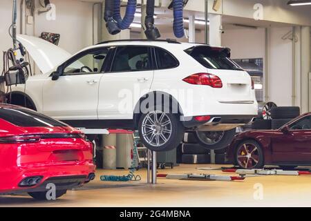Voitures relevées sur le pont élévateur en service auto, capot ouvert. Machines pour l'entretien, la réparation, le remplacement de pièces Banque D'Images