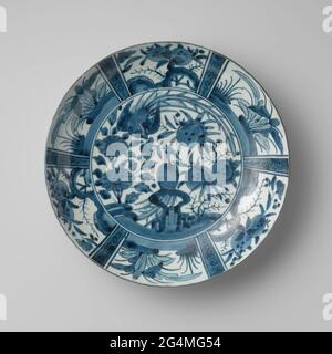 Plat avec deux Hoo-Birds près des plantes à fleurs. Plat en porcelaine, peint en bleu sous-brillant. Sur le plat un oiseau de foin sur une roche et un volant dans les plantes en fleurs (aster, grenade). Le mur intérieur est divisé en six compartiments avec une branche de grenade alternée et un bateau; les cours sont séparés par une boisson de fleur. Le mur extérieur avec un rang continu. Trois préen en bas. La performance suit la porcelaine d'écureuil chinois. Arita, bleu-blanc. Banque D'Images