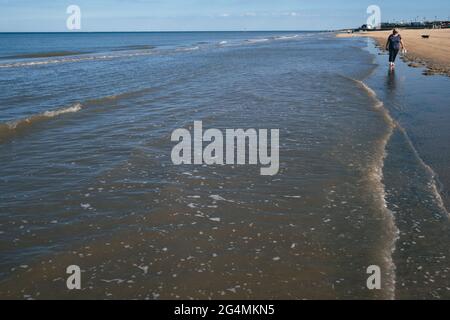 Une femme blonde d'âge moyen s'est promenée dans la mer le long de la rive nord de la plage de Mablethorpe dans le Lincolnshire Banque D'Images