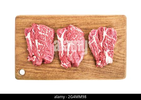 Steaks de bœuf crus sur planche à découper en bois isolés sur fond blanc avec passe-cheveux. Vue de dessus Banque D'Images