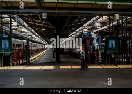 Hoboken, NJ, États-Unis — 19 juin 2021. Une femme à tête rouge marche dans une série de lumière à la gare de Hoboken, dans le New Jersey. Banque D'Images