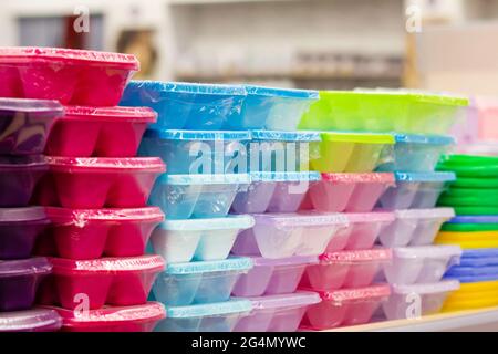 Photo des nouveaux contenants en plastique multicolore emballés empilés sur la tablette du magasin. Banque D'Images