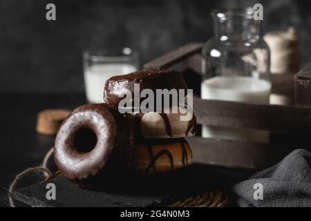 Pile de beignets frais avec glaçage au chocolat et au caramel sur une table décorée de noir Banque D'Images