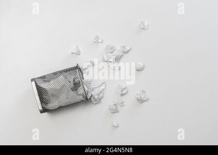 le bouquet de boules de papier froissé dans le panier de l'urne de poubelle en métal sur le fond coloré Banque D'Images