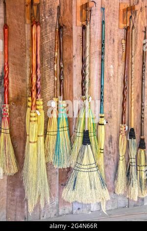 Balais à vendre - variété de balais décoratifs qui ressemblent à ils sont faits pour des sorcières et des sorciers et volant suspendu contre le mur en bois avec le prix Banque D'Images