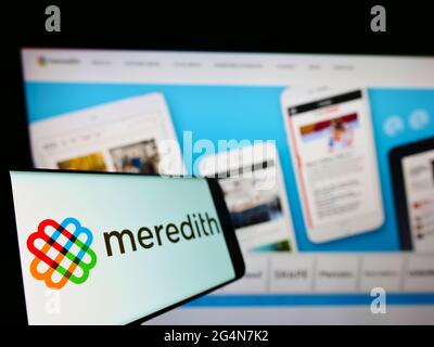 Smartphone avec le logo de la société de médias américaine Meredith Corporation à l'écran devant le site Web. Mise au point à gauche de l'écran du téléphone. Banque D'Images