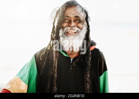 Portrait de rastafari ethnique ancien gai avec des dreadlocks regardant l'appareil photo dans la nature avec fond blanc Banque D'Images