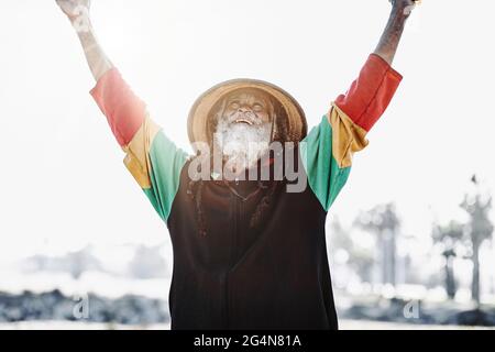 rastafari ethnique ancien gai avec des dreadlocks regardant l'appareil-photo dans un pré sec dans la nature Banque D'Images