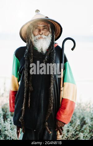 Portrait de l'ancien rastafari avec des dreadlocks regardant l'appareil photo dans la nature avec fond blanc Banque D'Images