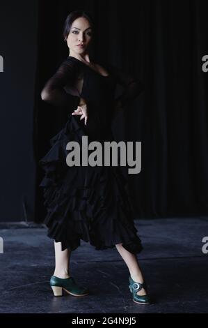 Jeune femme gracieuse en noir, dansant le flamenco tout en regardant l'appareil photo Banque D'Images