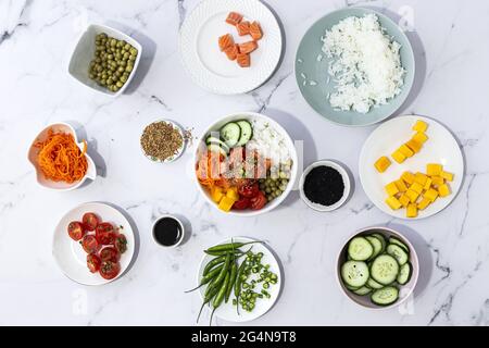 Vue de dessus de l'assortiment d'ingrédients frais pour la préparation traditionnelle de poke oriental placé sur une table en marbre Banque D'Images