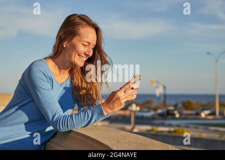 Vue latérale de la jeune femme heureuse surfeuse en combinaison allongée sur l'eau de mer et en appréciant la journée d'été Banque D'Images