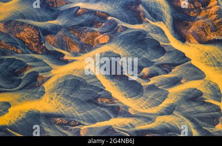 De dessus vue aérienne de la rivière avec l'eau orange qui coule à travers la campagne rugueuse en Islande Banque D'Images