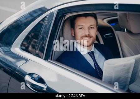 Jeune homme élégant lit journal sur backseat of car Banque D'Images