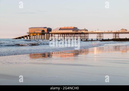 Jetée de Cromer au coucher du soleil vue en juin 2021 depuis la plage ouest avec le soleil illuminant la plage de sable. Banque D'Images