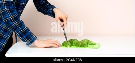 main avec un couteau coupé avocat sur la planche dans le kithcen à la maison Banque D'Images