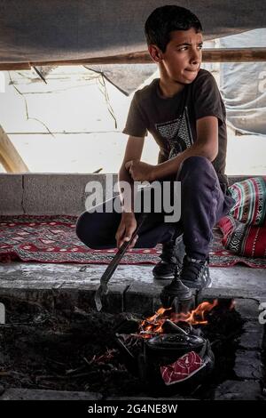 BIR Hadaj, Israël. 22 juin 2021. Un jeune homme prend la responsabilité de préparer du thé et du café sur une fosse à feu ouvert dans la tente des visiteurs de la ville bédouine de Bir Hadaj. La bataille politique de plusieurs décennies pour les villages bédouins non reconnus et le développement de ceux qui sont déjà légalisés dans le Negev israélien a pris le pas comme nouveau gouvernement d'unité Bennett - Lapid dépend du soutien des votes des quatre sièges de la Knesset appartenant à la Raam, liste arabe unie. Crédit : NIR Amon/Alamy Live News Banque D'Images