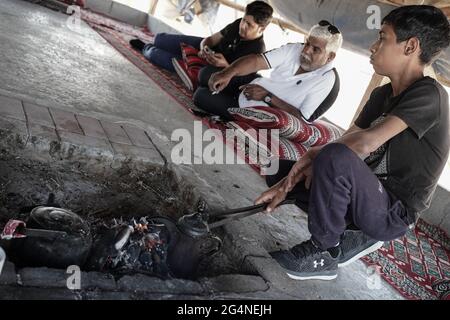 BIR Hadaj, Israël. 22 juin 2021. Un jeune homme prend la responsabilité de préparer du thé et du café sur une fosse à feu ouvert dans la tente des visiteurs de la ville bédouine de Bir Hadaj. La bataille politique de plusieurs décennies pour les villages bédouins non reconnus et le développement de ceux qui sont déjà légalisés dans le Negev israélien a pris le pas comme nouveau gouvernement d'unité Bennett - Lapid dépend du soutien des votes des quatre sièges de la Knesset appartenant à la Raam, liste arabe unie. Crédit : NIR Amon/Alamy Live News Banque D'Images