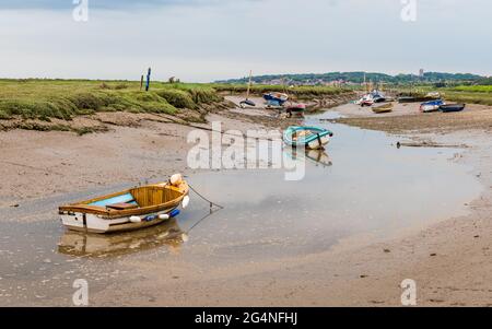 Des bateaux amarrés dans un chenal d'eau à Blakeney à marée basse sur la côte nord de Norfolk, photographiés en juin 2021. Banque D'Images