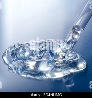 Échantillon de sérum liquide transparent avec pipette sur fond de verre bleu. Produit cosmétique pour les soins de la peau ou gel liquide transparent médical. Carré Banque D'Images