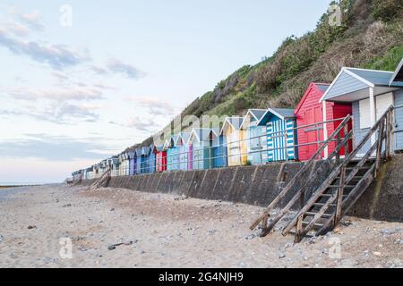 Des cabanes de plage colorées bordent la promenade de Cromer avant le coucher du soleil sur la côte nord de Norfolk en juin 2021. Banque D'Images
